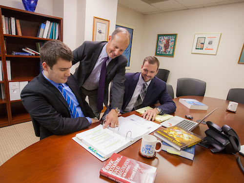 Accounting students sitting at a table working with a professional accountant