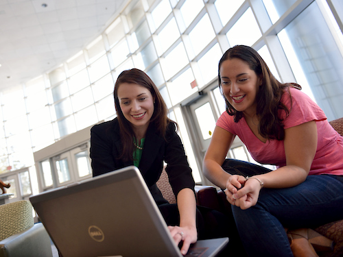 Two students in Widener's University Center working on a laptop on a sunny day