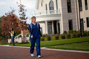 Widener Nursing student walking outside nursing building, Founders Hall, in fall