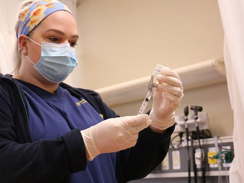 Nursing student in face mask preparing vaccine