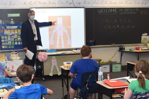 EdD graduate Ken Batchelor standing at a screen in front of a classroom