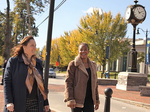Admissions administrator walks with a student on campus