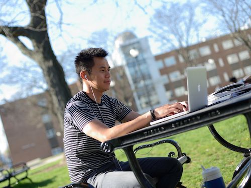 Student working on laptop outside.