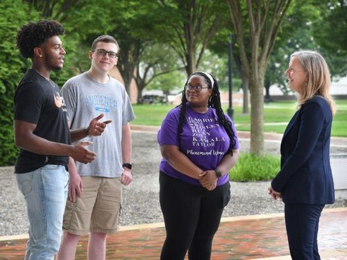 Stacey Robertson talks with female and male students on campus.