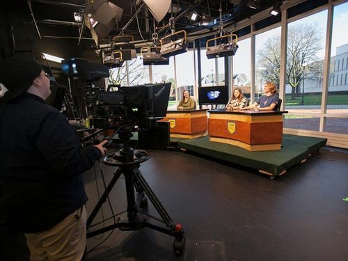 Students on WUTV production 500x375 A camera operator films students at a news desk in Widener's WUTV studio.