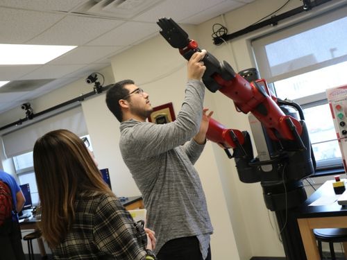 Students in Widener robotics lab 500x375 A male student examines a robotic arm in Widener's robotics lab.