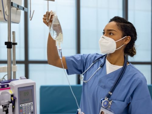 Nurse in blue scrubs examining IV bag