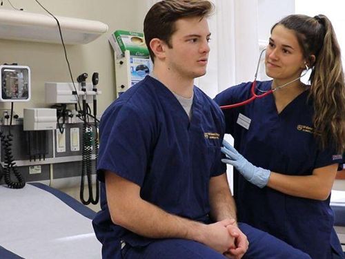 Two Nursing Students Practice in a Simulation Lab Taking Turns with Nurse and Patient Roles