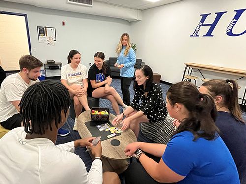 Student-athletes gathered around playing a game in the H-U-B space
