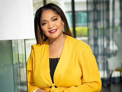 Dr. Pamela McCauley, wearing a yellow and black blouse, poses for a photo in an office