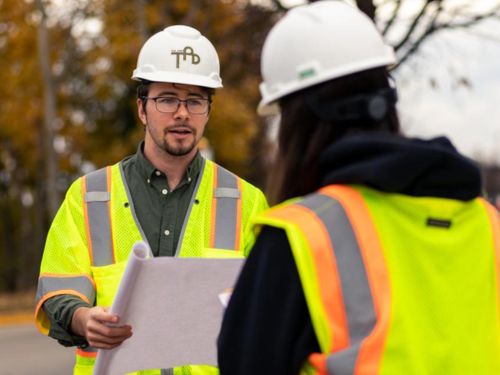 Construction management professional speaks with colleague.