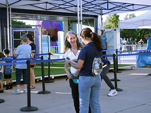 A student talks to a fan for a survey in front of a tent and other fans outside the Philadelphia Union's stadium