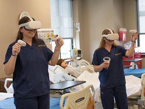Two nursing students wear oculus headsets to practice in virtual simulated clinical settings