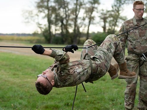 Kevin Draeger in Army fatigues moves across a rope upside down