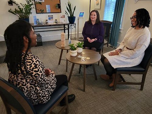 Three people sit and talk in the lobby of the CAPS building