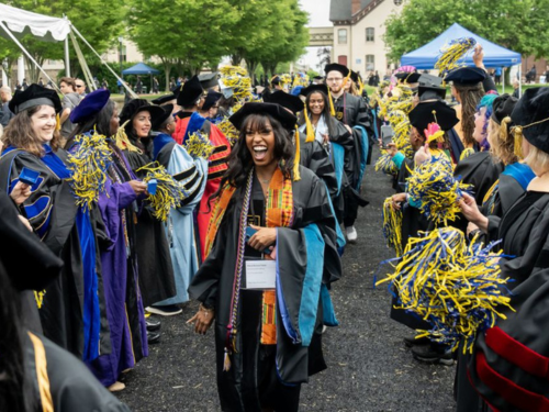 Graduates walk through a sea of pom poms at commencement