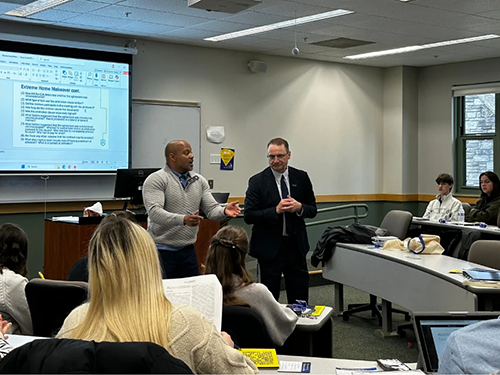Law school deans Todd Clark and andré douglas pond cummings stand in front of a classroom speaking to students