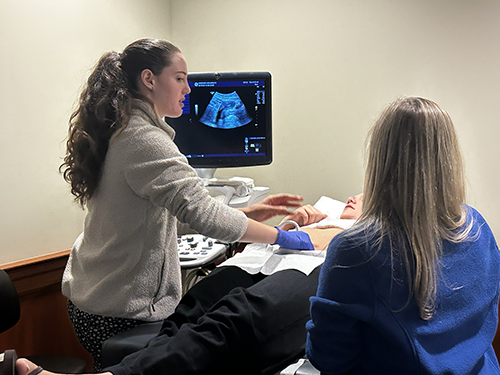 A student and faculty member conduct an ultrasound on a student patient