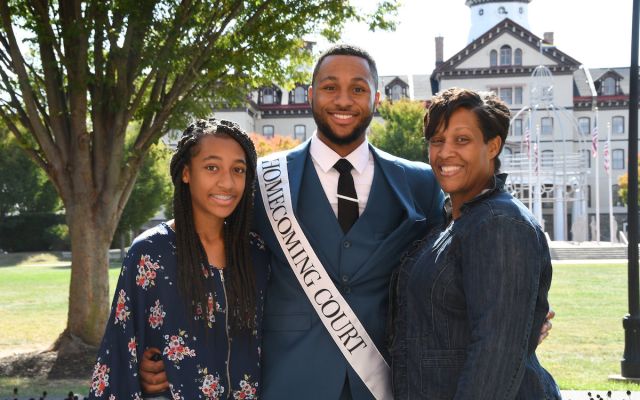 family celebrates student in homecoming court in front of Old Main building