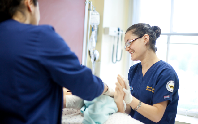 Two nursing students working with a mannequin in a Widener simulation lab.