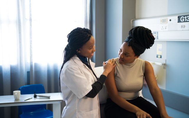 Physician assistant speaking with patient, with hand on patient's shoulder