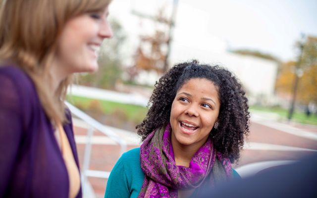 Two students having a conversation on Widener's campus in fall