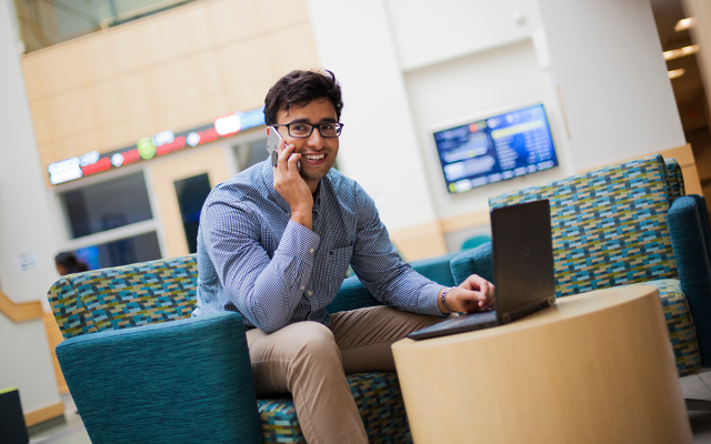 Student on laptop and talking on the phone in Widener's business building