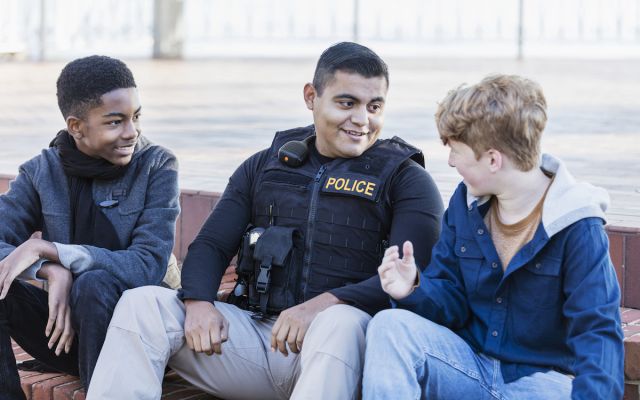 A police officer sitting with two children. 