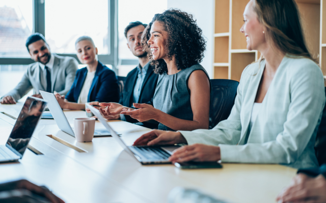 Business professionals sit at a table and talk during a meeting.