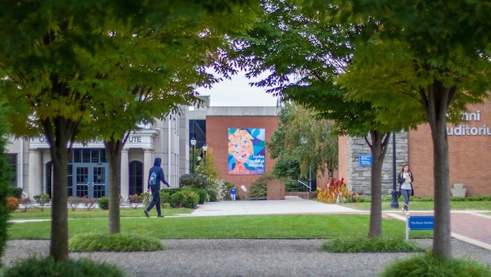 students walking campus in front of Kapelski Leadership Banner