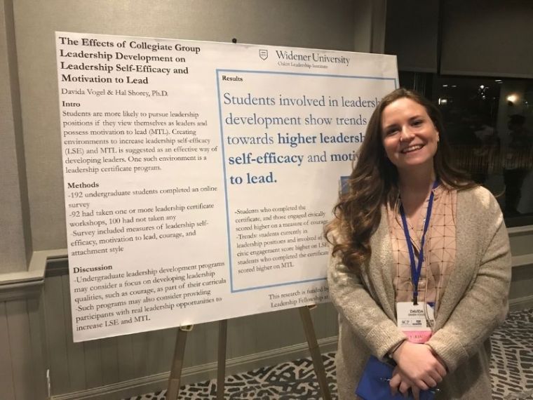 Davida Vogel poses in front of a research poster