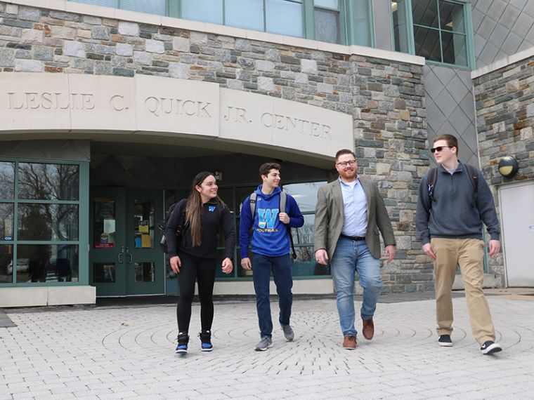 Ryan Raiker walks in front of Quick Center with three students
