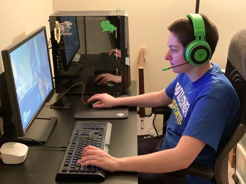 Hayley Bonhage, wearing headphones, sitting at a computer playing Overwatch for Esports team