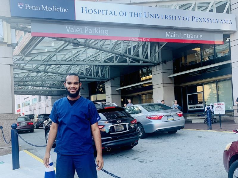 Jeremiah McFarland, standing outside a hospital, wearing blue scrubs