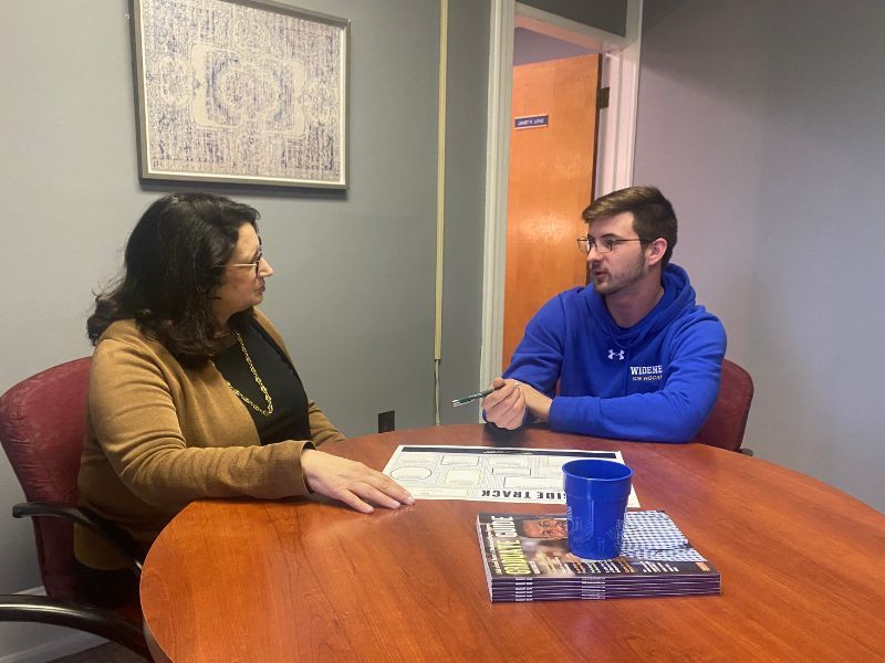 A female administrator sits with a male student discussing career planning.