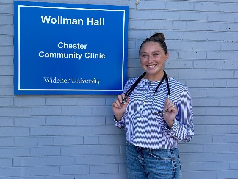 Taylor Wise poses in front of the Chester Community Clinic with her stethoscope draped around her neck.