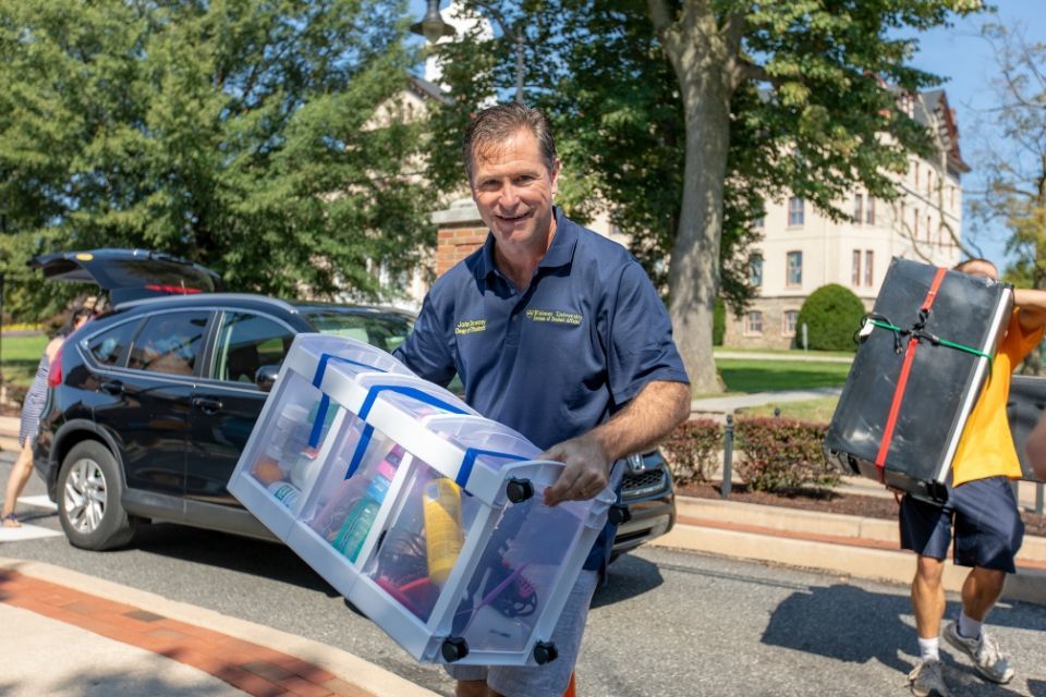 Dean of Students John Downey helps carry student belongings on move-in day.