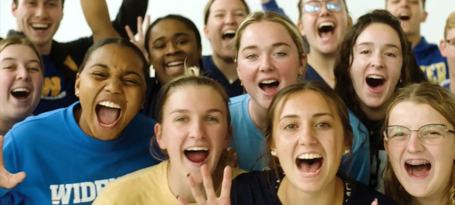 Group of Widener students cheering in front of a white screen